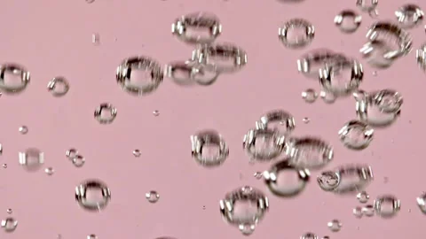 Macro shot of air bubbles in water rising up on light pink background. Slow Stock Footage 167306363