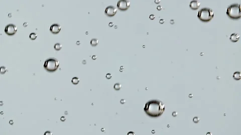 Macro shot of air bubbles in water rising up on light blue background. Slow Stock Footage 168736563