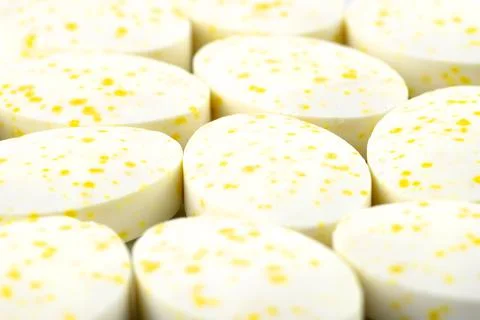 A macro shot of a background made of white candies with yellow spots. Stock Photos