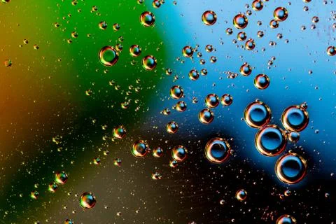 Macro shot of backlit liquid with small bubbles in it over colored background. Stock Photos