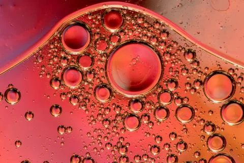 Macro shot of backlit liquid with small bubbles in it over colored background. Stock Photos