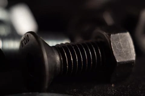Macro shot of a black solid screw on the ground with a blurry background 写真素材