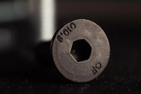 Macro shot of a black solid screw on the ground with a blurry background Stock Photos