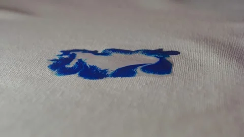 Macro Shot of Blue Paint Diffusing into Water on Textured Canvas Fabric Video stock 327515055