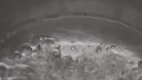 Macro shot of boiling water process. Close-up of steamy water with bubbles in Stock Footage 126206168
