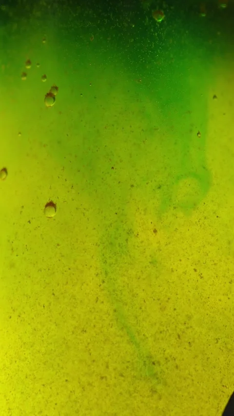 Macro shot of a bright yellow-green fluid with suspension swirl and tiny air Stock Footage 340637605