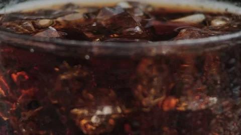 Macro shot of bubbles and ice in Cola, drops of water flowing down the glass, . Video stock 141818432