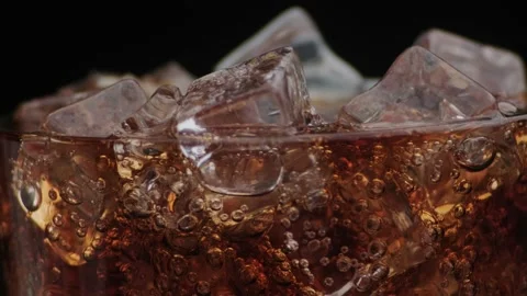 Macro shot of bubbles and ice in Cola, drops of water flowing down the glass. 動画素材 141819860