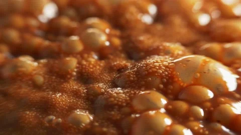 Macro shot of bubbles in boiling thick brown liquid, shallow depth of field. Stock Footage 172445920