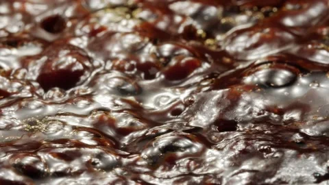 Macro shot of bubbles in boiling thick dark brown liquid, backlit. Stock Footage 221870291