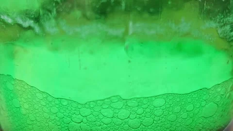 Macro shot of bubbles forming on top of a bright green liquid Stock Footage 334186167