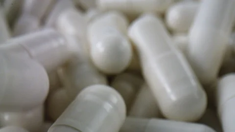Macro shot of a bunch of white pills piling up in slow motion Stock Footage 105599860