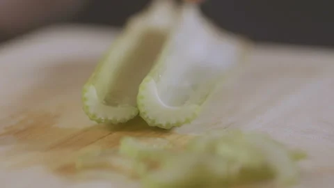 Macro shot of celery being sliced on wooden chopping board. Stock Footage 90800838