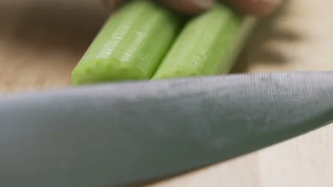 Macro shot of celery being sliced on wooden chopping board Stock Footage 101456251