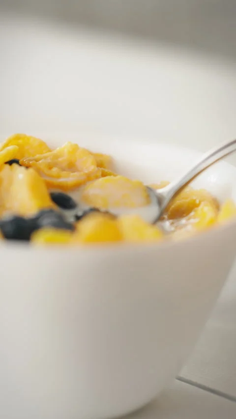 Macro shot of cereal flakes and berries with milk in a bowl and spoon Stock Footage 331603168