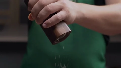Macro shot: chef uses salt mill to add some salt for his meal, salt falls in Stock Footage 114215968