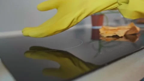 Macro shot of cleaning spray being applied to a black electric stove for effecti Stock Footage 301868820