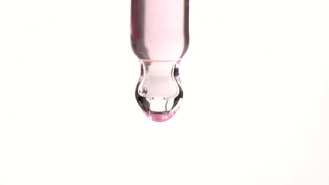 Macro shot of clear serum dripping from glass pipette on white background. .. Stock Footage 294173834