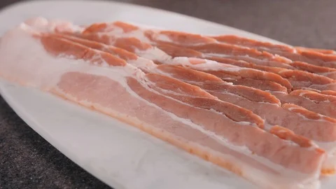 Macro shot of cut thin bacon slices pieces on the white cutting board Video stock 102655121