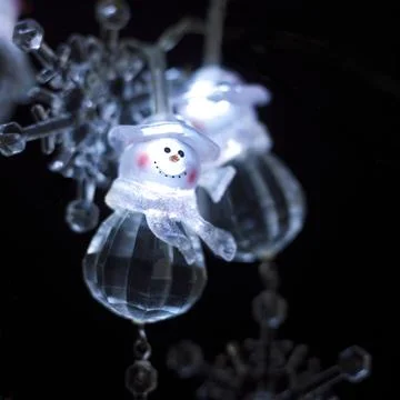 A macro shot of cute string Christmas lights shaped like a snowman on a black Stock Photos