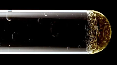 Macro Shot of Different Sized Gold Bubbles in descending in Glass Test Tube on Stock Footage 270937805