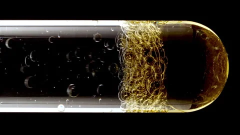 Macro Shot of Different Sized Gold Bubbles in descending in Glass Test Tube on Stock Footage 274150557