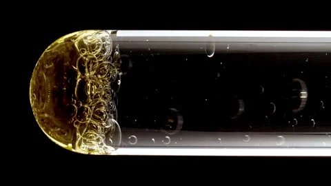 Macro Shot of Different Sized Gold Bubbles in descending in Glass Test Tube on Stock Footage 274638546