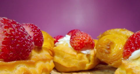 Macro shot of donuts with cream and strawberry slices on a dark rosy background Stock Footage 181540313