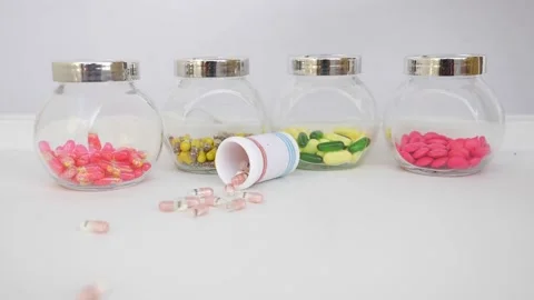 Macro shot of dropping capsule bottle on a white table with colorful tablets Stock Footage 147699829