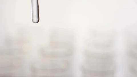 Macro shot of a dropping glass which fills test tubes Video stock 100559176