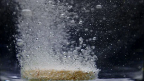 Macro shot of effervescent tablet dissolves with bubbles in water, slow motion Stock-Footage 141985403