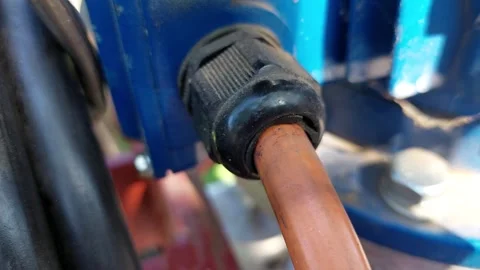 Macro shot of an electric cable entering a blue industrial motor through a black 库存影片 336008102
