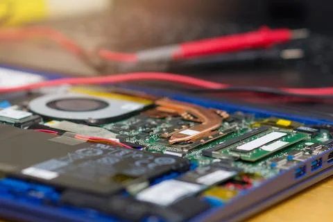 Macro shot of an electronic microcircuit and a multimeter lying on a laptop. Stock Photos