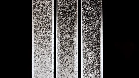 Macro shot of fine air bubbles rising in water in glass test tube on black Stock Footage 266940739