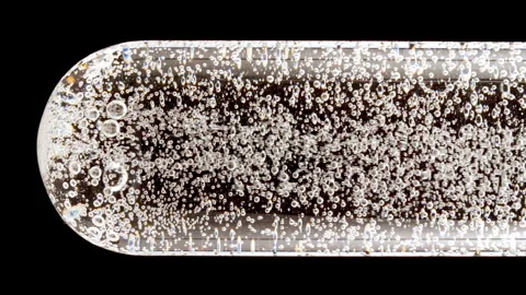 Macro shot of fine air bubbles rising in water in glass test tube on black Stock Footage 274150522