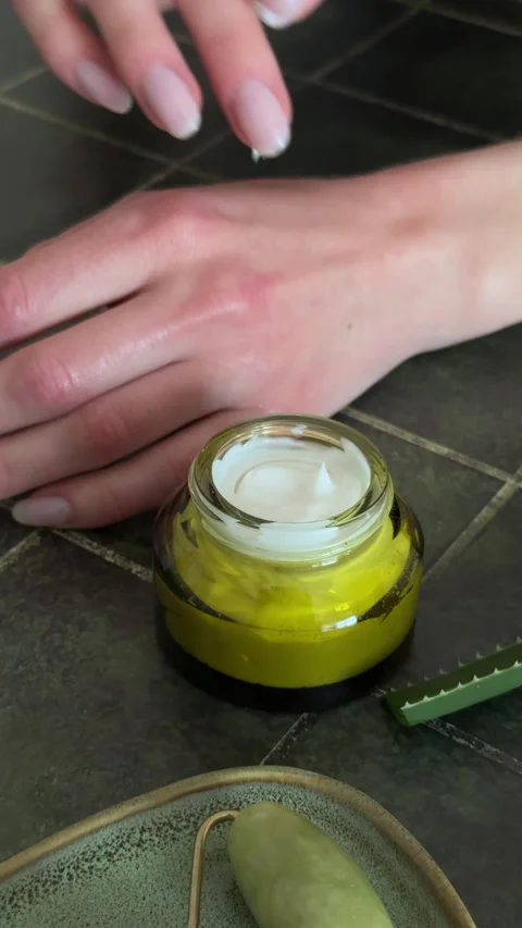 Macro shot of a finger touching white moisturizing cream in a glass jar, Stock Footage 332490862