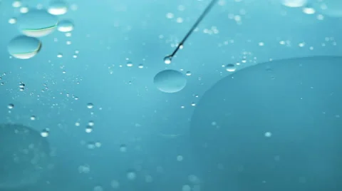 Macro shot of floating oil drops and syringe on water Stock Footage 55510339