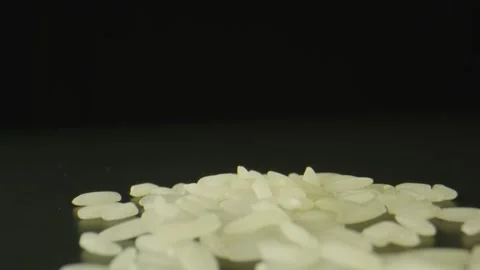 Macro shot of grains of rice on top of black table, black background Stock Footage 131689180