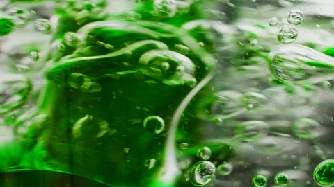 Macro shot of green bubbles getting mixed in water with a stick Video stock 124671140