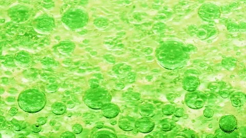 Macro shot of green bubbles in water floating right with yellow background Video stock 124671051