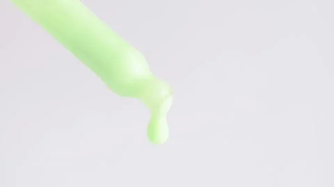 Macro shot of green moisturizing serum lotion falling from a glass pipette Stock Footage 271122741