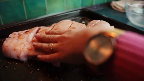 Macro shot of a hand spreading dry spices over scored pork belly on a baking Stock Footage 328870710