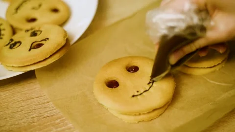 Macro shot of hands decorating a pumpkin cookie with melted chocolate Stock Footage 342704211