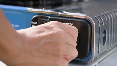 Macro shot of hands locking and turning the ignition dial knob on a portable Stock Footage 339092828