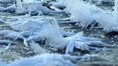 Macro shot of ice crystals, known as frost flowers, on a frozen surface 動画素材 334693046
