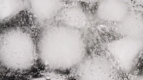 Macro shot of ice cubes in water and air bubbles on black background. Pouring Vídeo Stock 165057550