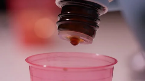 Macro Shot of Liquid Drops Falling from Dropper into Medicine Cup Stock Footage 338364882