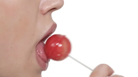 Macro shot of lower face of Caucasian woman seductively licking lollypop. Side Stock Footage 136975373