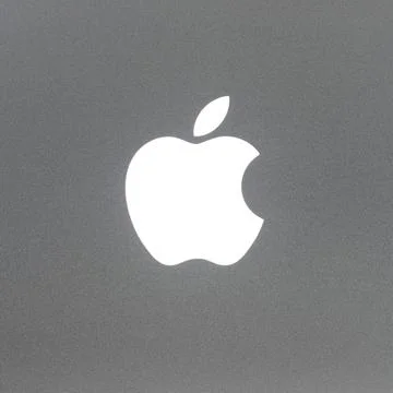 Macro shot of MacBook Pro backlit Apple logo, brushed aluminium texture. Stock Photos