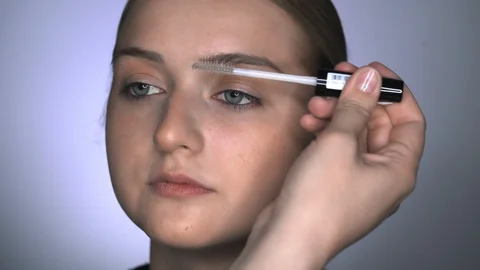 Macro shot of makeup artist making professional make-up for young woman in Stock Footage 128196900